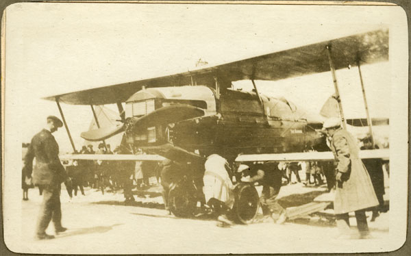The aircraft the Raymore surrounded by people examining the aircraft, including a man in a greatcoat and another who looks to be a soldier.