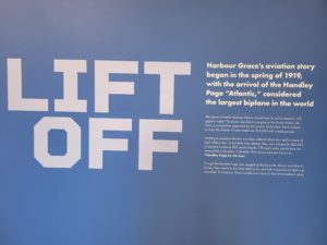 Against a blue background, big white block letters read Lift Off. Next to this, in bold, reads, Harbour Grace's aviation story began in the spring of 1919, with the arrival of the Handley Page "Atlantic," considered the largest biplane in the world. More is written under that but it is unclear in the picture.